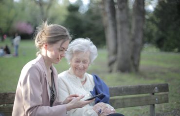 daughter explaining elderly mother how using smartphone
